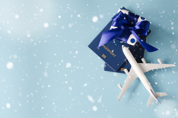 Christmas or New Year travel concept. Toy airplane with passports and gift box on blue background.