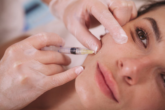 Cropped close up of a beautiful woman getting filler injections in her face. Young woman receiving hyaluronic acid injections by cosmetologist