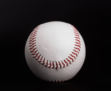 closeup on a white baseball ball with red thread, black background