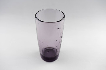 Glass of dark glass with drops of water on a white background.