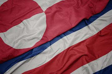 waving colorful flag of costa rica and national flag of greenland.