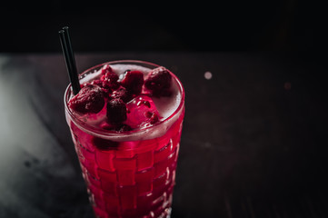 red alcohol coctail on the table with raspberry