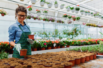 Young woman working in beautiful colorful flower garden greenhouse