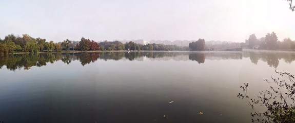 Reflection of trees in the lake during fall season - panorama