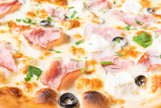 Cheap pizza with curd cheese, ham, olives, and herbs.