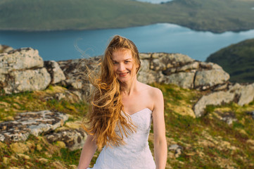 Fototapeta na wymiar Bride in wedding dress in mountains looking to camera