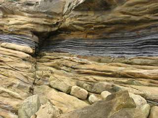 Sandstone and shale layers and textures in a coatal cliff worn by wave action.