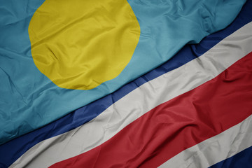 waving colorful flag of costa rica and national flag of Palau .