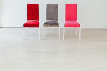 three multicolored chairs in the interior of an empty white room