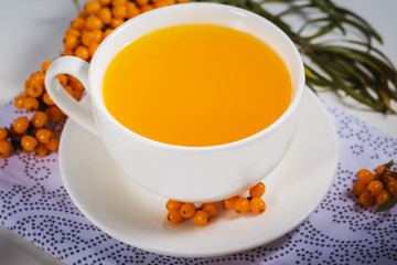 sea-buckthorn tea in white cup with  berries with branch on natural napkin. a source of nutritional vitamins in the fall and winter