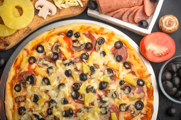 Pizza with ingredients, tomatoes, salami, mushrooms, mazzarella sauce and cheese and pizza knife. Italian pizza, culinary recipes concept, menu, restaurant, gourmet cuisine.