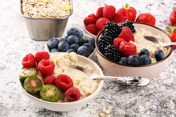Bowl of oatmeal porridge with banana, raspberries coconut and caramel sauce on rustic table, hot and healthy food for Breakfast