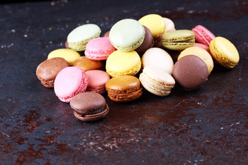 Sweet and colourful french macaroons or macaron on dark black background, Dessert.