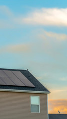 Vertical Exterior view of a home with solar panels on the roof under blue sky and clouds