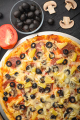Italian pizza with ingredients on a dark background. Vertical photo.