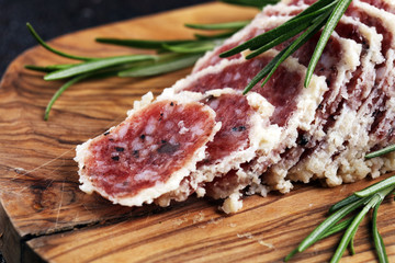 Salami truffle. The saltufo is a piece of salami mixed with summer truffle on rustic background