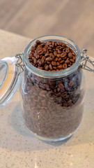 Vertical frame Open glass jar of fresh roasted coffee beans