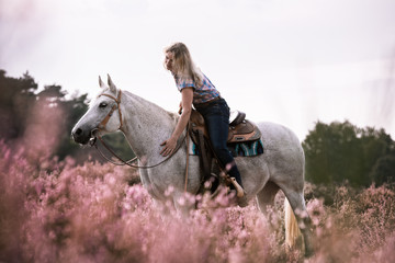 Frau lobt Pferd in der blühenden Heide