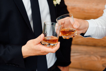Two glasses with whiskey in men's hands. Alcohol. Celebration.