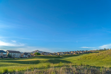 Fototapeta na wymiar Grass covered golf course with homes in the background viewed on a sunny day