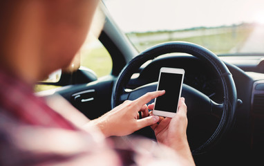 Man typing a message while driving a car, close up photo. Dangerous driving. Transportation concept