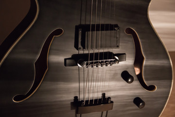 Fototapeta na wymiar Black jazz archtop guitar with holes. hollow steel-stringed acoustic or semiacoustic