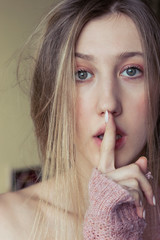 Naklejka premium Blonde woman with green eyes showing shh sign