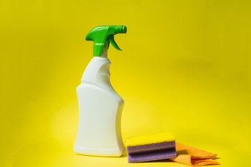 Detergent, sponge and gloves for cleaning the house on a yellow bright background. The concept of cleaning, cleansing and bleaching