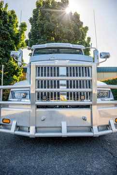 Front Of Big Rig Semi Truck Tractor With Powerful Grille Bumper Guard Rest On The Truck Stop Parking Lot In Sunshine