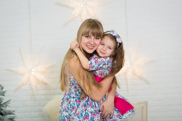 Happy loving family. Mother and her daughter child girl in the same dresses playing and hugging.