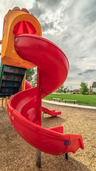 Vertical Close up on the colorful spiral slide at a park with cloudy sky background