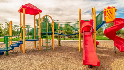 Panorama frame Focus on empty childrens playground at a park with red slides and climbing bars