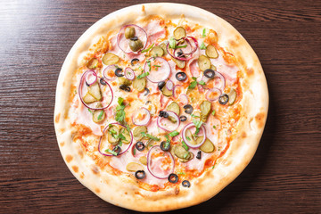 Cheap pizza with ham, onion, pickled cucumbers and olives.