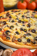 Italian pizza with ingredients on a dark background. Vertical photo.