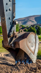 Vertical Focus on the bucket and arm of an excavator digging soil at a construction site