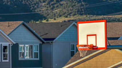 Naklejka premium Panorama frame Focus on a basketball court with homes and mountain background on a sunny day