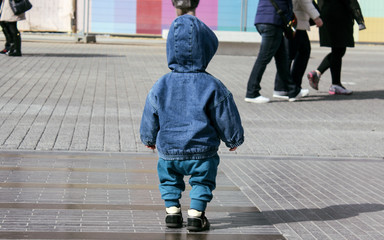 Toddler boy lost on the street. Wearing denim jacket with hood. Baby boy without parents,crowded street.