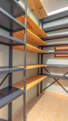 Vertical Interior of a small empty closet with metal and wood shelves for clothes