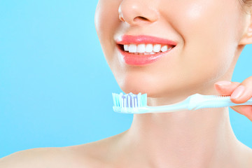 Young beautiful woman is engaged in cleaning teeth. Beautiful smile healthy white teeth. A girl holds a toothbrush. The concept of oral hygiene. Promotional image for a stomatology, dental clinic.