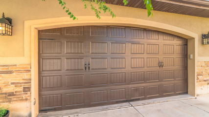 Panorama Garage door with an arched design against the concrete and brick wall of a home