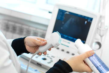 Doctor prepare an ultrasound machine for the diagnosis of a patient. Doctor puts media gel on an...