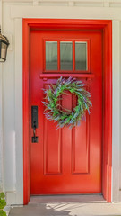 Fototapeta na wymiar Vertical Red front door of modern home with green wreath
