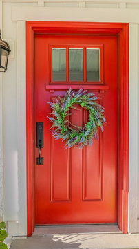 Vertical Red front door of modern home with green wreath