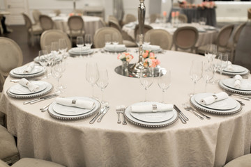 The white round banquet table in the restaurant is decorated with fresh flowers. Stylish event decor