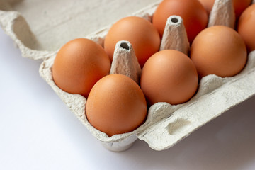 Stack of many brown and speckled fresh raw chicken eggs in the cardboard tray box packaging for sale in supermarket.