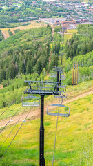 Fototapeta na wymiar Vertical frame Chairlifts with amazing view of ski resort blanketed in greenery at off season