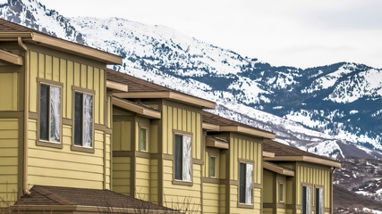 Panorama Close up of facade of townhomes with snowy mountain and cloudy sky background