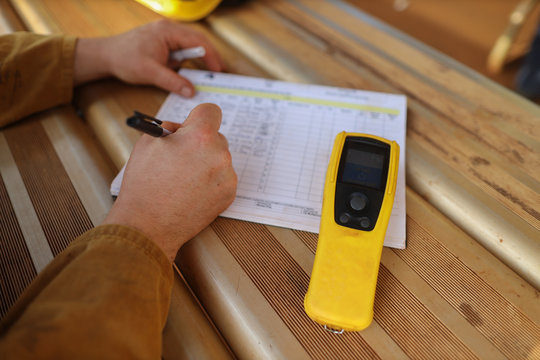 Construction miner writing zero alcohol in the blood system on the daily sheet prior to work with breathalyser breath alcohol testing equipment beside him on construction mite site Sydney    