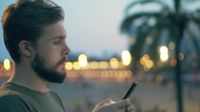 Young man on beach using smartphone
