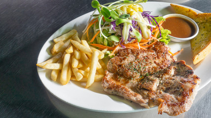 Pork steak with french fries on a white dish